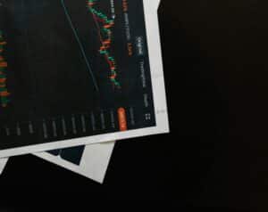 Tilted printed dark chart with multiple colorful line graphs and an orange data badge along the right edge; labels such as Original and TrainView visible, placed on white paper atop a dark surface.