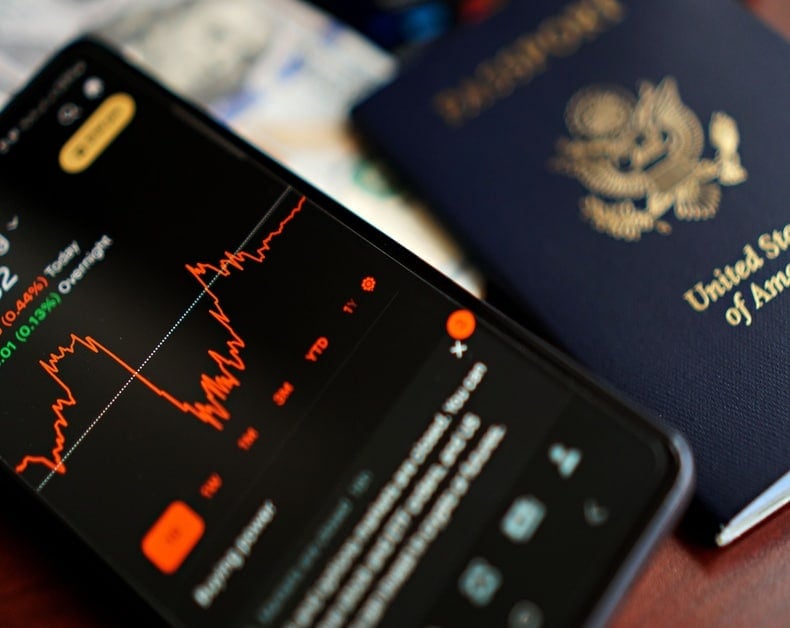 Smartphone screen displaying a red stock chart with a United States passport in the background