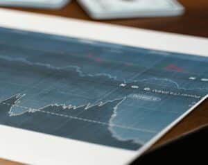 Printed financial chart showing a fluctuating stock price with a blue grid and indicators on paper on a desk