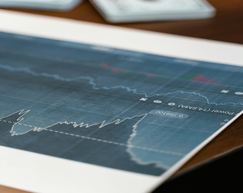 Printed financial chart showing a fluctuating stock price with a blue grid and indicators on paper on a desk