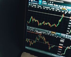 Laptop screen displaying Bitcoin price chart with green and red candlesticks and a time axis for price movements.