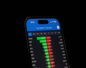 Smartphone screen showing a stock market app with 'Top Gainer / Top Loser' and green/red percentage changes in the list.