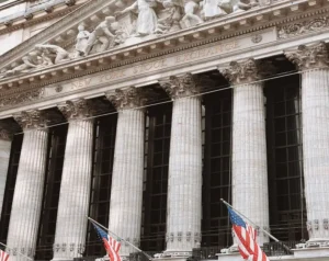 Front facade of the New York Stock Exchange with tall columns and American flags
