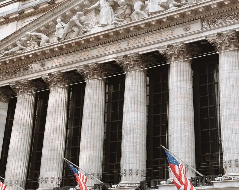 Front facade of the New York Stock Exchange with tall columns and American flags